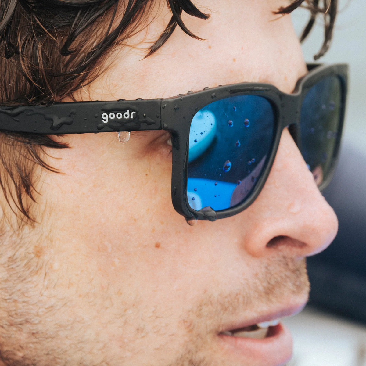 Fit and style showcase of black sunglasses with blue reflective lenses. Water repellent and capable of floating.