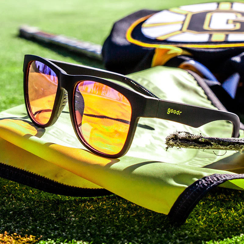 Product close up of large, square-shaped black sunglasses with rose-tinted high contrast lenses.